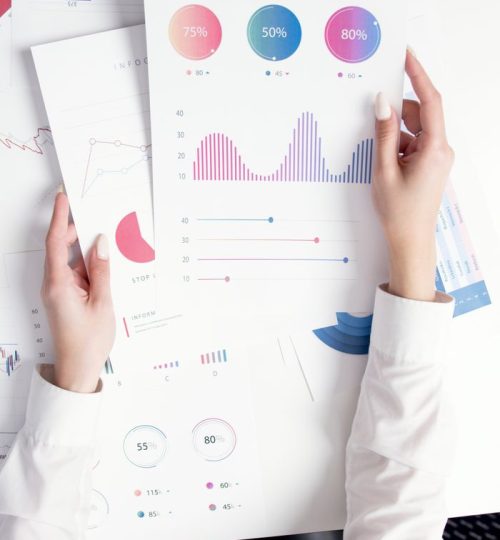 Close-up of hands analyzing colorful business data reports in an office setting.