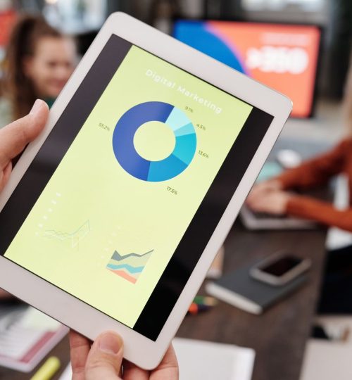 Business team reviewing digital marketing statistics on a tablet during an indoor meeting.