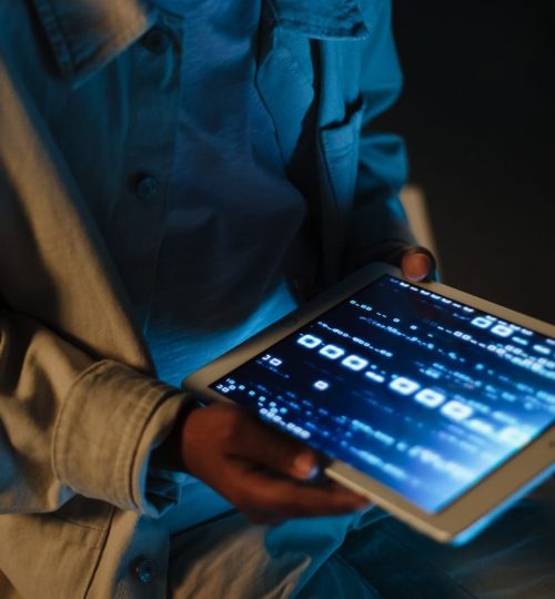 Close-up of a person using a tablet device indoors with code visible on the screen.
